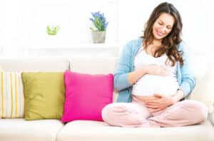 35560982 pregnant woman sitting on a sofa and caressing her belly